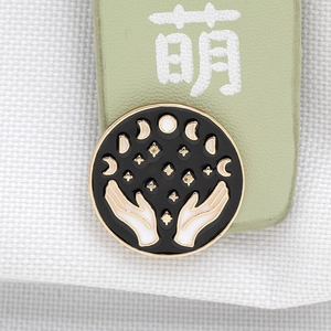 Detailed macro view of enamel moon phase brooch with mystical hands and stars pattern