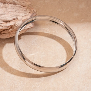 Detailed view of polished silver metal bangles on a textured marble background