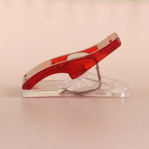 Macro side view of red translucent plastic sewing clips with metal springs for quilting