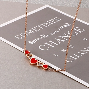 Detailed view of rose gold necklace featuring five connected hearts with red enamel inlay