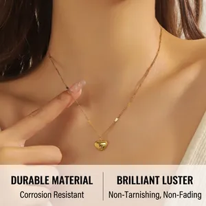 Detail of gold heart pendant with Love engraving and sequin chain on model neck