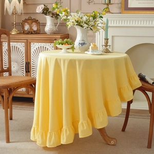 Detail of yellow round washed cotton tablecloth with elegant ruffled edges in home setting