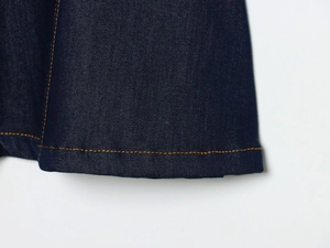 Détail de couture double orange sur tissu denim bleu foncé de haute qualité