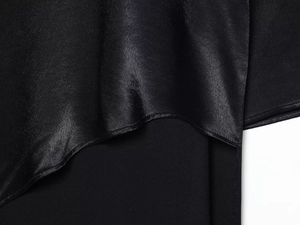 Gros plan du tissu en satin noir élégant montrant la texture lisse et le drapé brillant