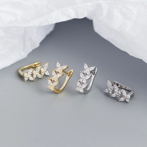 Flat lay of four butterfly U-shaped earrings in gold and silver with crystal pavé