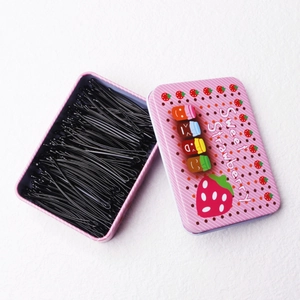 Pink metal storage tin with cartoon strawberry design filled with black metal bobby pins