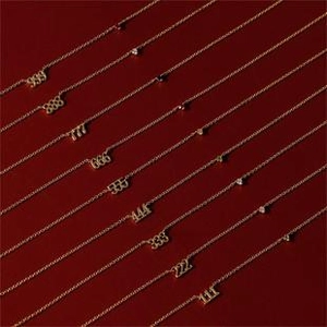 Gros plan de colliers dorés avec pendentifs chiffres 111-999 et cristaux sur fond rouge