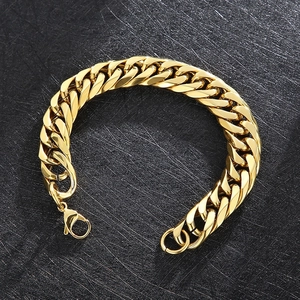 Close-up of golden flat Cuban link bracelet with lobster clasp on dark textured background