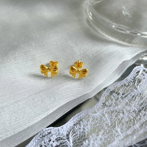 Elegant gold bow earrings in titanium steel with silk and lace decorative background