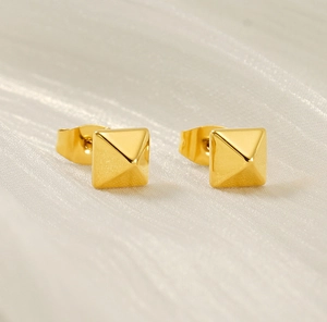 Vue macro des boucles d'oreilles pyramides dorées avec finition mate sur tissu doux