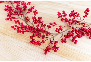 Close-up of bright red artificial Christmas berries on natural light wood texture