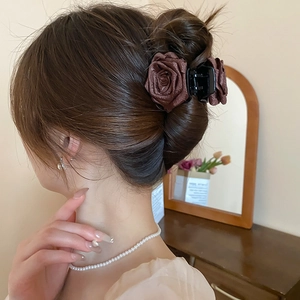 Rückansicht einer dunkelbraunen Organza-Rosen-Haarklammer in einer eleganten Dutt-Frisur
