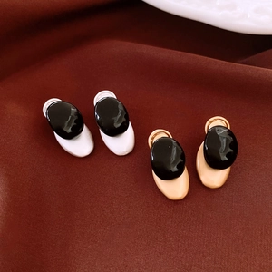 Detail view of oval black resin earrings with gold and silver alloy bases on fabric