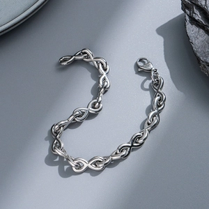 Detailed view of silver stainless steel curb chain bracelet with lobster clasp on rock
