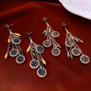 Détails de boucles d'oreilles ethniques à pompons avec strass sur satin rouge