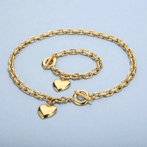 Detail of gold heart pendant jewelry set featuring Cuban chain and T-bar toggle clasp
