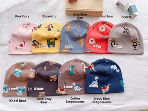 Detailed flat lay of colorful cotton knit baby beanies featuring various cartoon prints