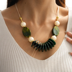 Detail of layered green acrylic oval pendant and beige beads on a vintage leather necklace
