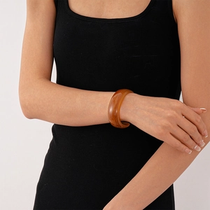 Close-up of vintage amber resin cuff bracelet with marble texture on female wrist