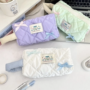 Quilted storage bags in pastel colors with bow details and cute patch on desk