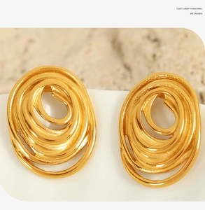 Macro detail of golden spiral titanium steel earrings with a polished artistic texture