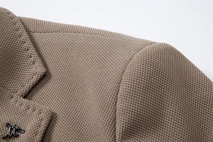 Vue macro de la texture tricot abricot et bouton métallique argenté sur le blazer