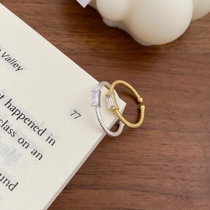Artistic close-up of gold and silver twisted rings with square zircon on book pages