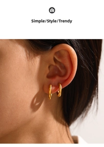 Close-up of polished gold hoop earrings showing the glossy finish on a model's ear