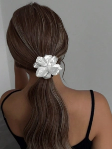 Detail view of a white flower hair clip with pearl center on a low ponytail