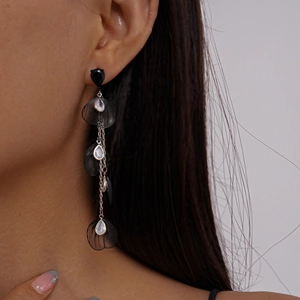 Détail de boucles d'oreilles à franges et pétales noirs portées par un mannequin
