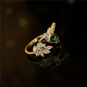 Gold plated hummingbird and leaf open ring with green stones and white crystals