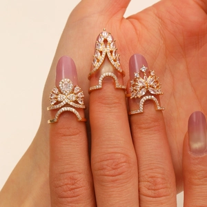 Close-up of gold plated nail rings set with sparkling cubic zirconia on fingers