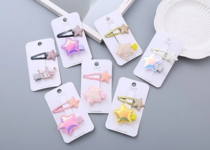 Close-up of sparkling glitter star and crown hair clips on handmade card display