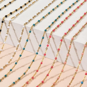 Colliers en perles colorées avec chaînes dorées disposés sur des socles blancs