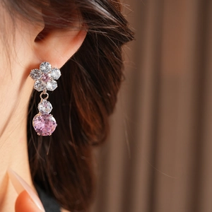 Detailed view of elegant pink flower zircon earrings worn on a model in warm lighting