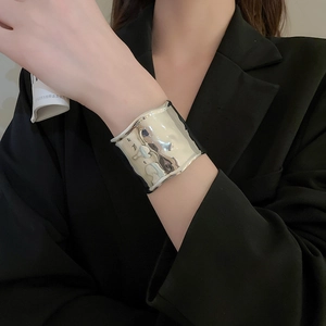 Detail of silver hammered texture cuff bracelet showing irregular reflective metallic surface