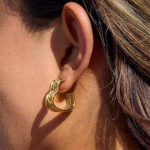 Close-up of 18K gold-plated stainless steel triple C hoop earrings with woven texture on model