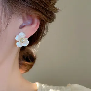 Elegance with white pearl flower stud earrings featuring a sparkling zircon center on model