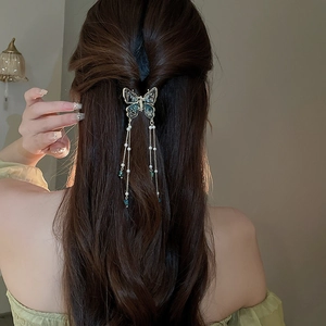 Elegant gold butterfly hair claw clip with pearls and long tassels on half-up hairstyle