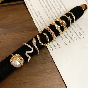 Detail view of gold ring set with pearls and pink crystals on a black display stand