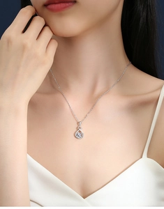 Close-up of heart-shaped moissanite pendant on silver chain worn by a female model