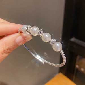 Detailed close-up of a layered silver bracelet with five large pearls and pavé diamonds