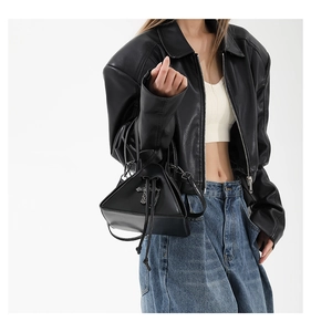 Detail of black punk triangular handbag with metallic cross and smooth leather texture
