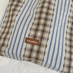 Close-up of vintage plaid patchwork tote bag featuring blue stripes and brand leather tag