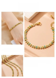 Macro detail of gold plated leaf chain bracelet with colorful enamel charms and lobster clasp