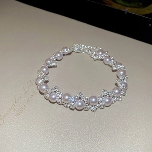 French irregular pearl bracelet with sparkling zircons on a textured beige surface