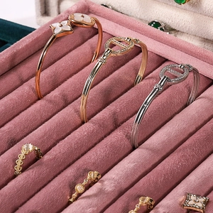 Elegant velvet jewelry display tray featuring assorted gold rings and clover bangles