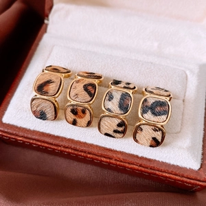 Close-up of geometric square earrings with 18K gold plating and leopard print finish