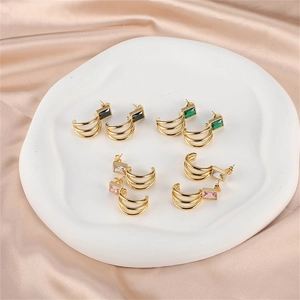 Three-layer gold hoop earrings with multi-color zircon stones on white ceramic tray