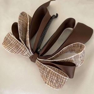 Detail of tweed and satin ribbon bow hair clip with a black plastic banana clip base